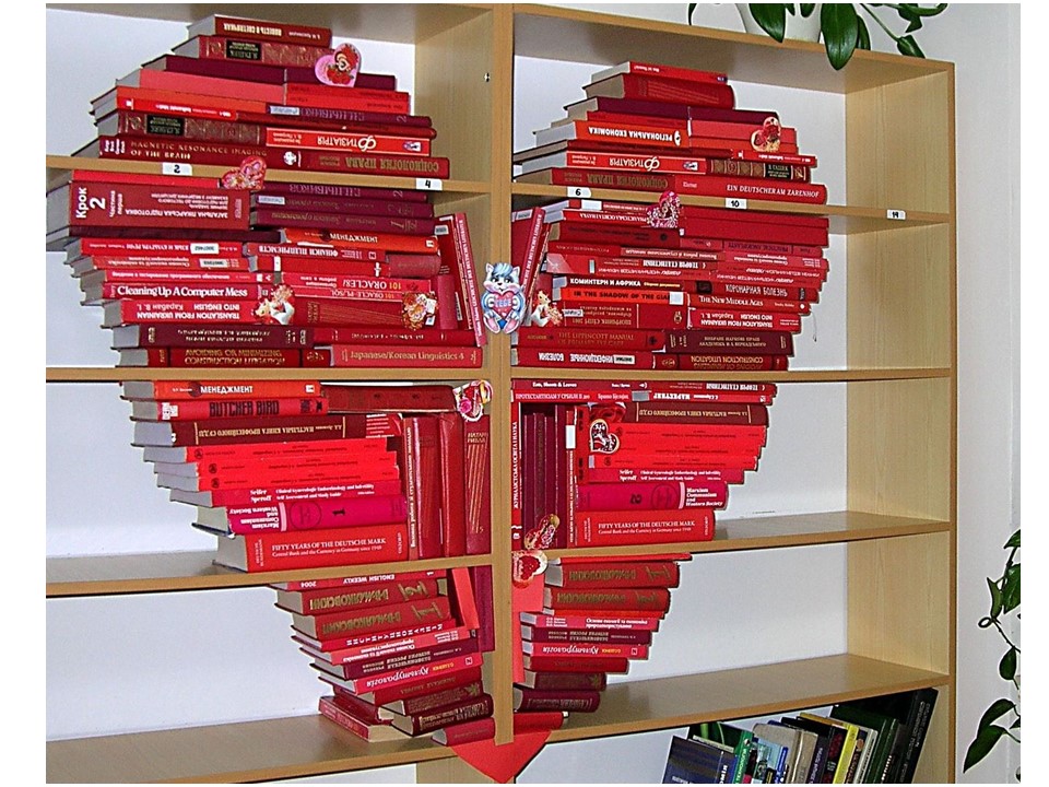 Книги в красных обложках выложены на стеллаже в виде сердца