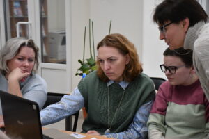 Три дамы за ноутбуком на курсах повышения квалификации с преподавателем