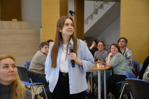 Куратор смотрит на интерактивную доску и оценивает выполнение командами заданий